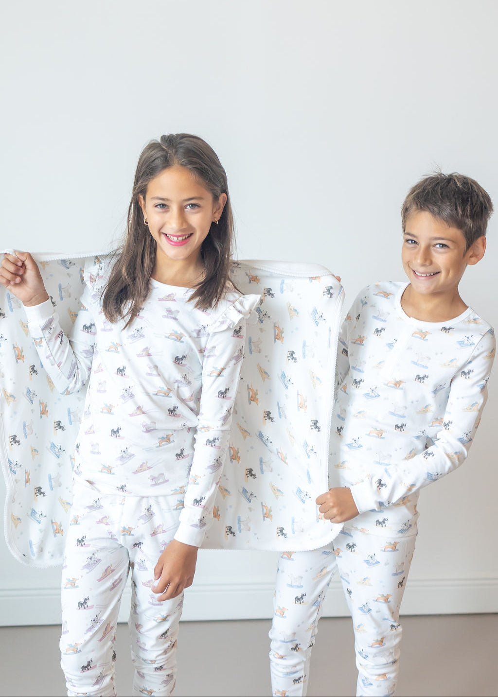 Two children wearing matching pajamas with a pattern, standing against a plain background.