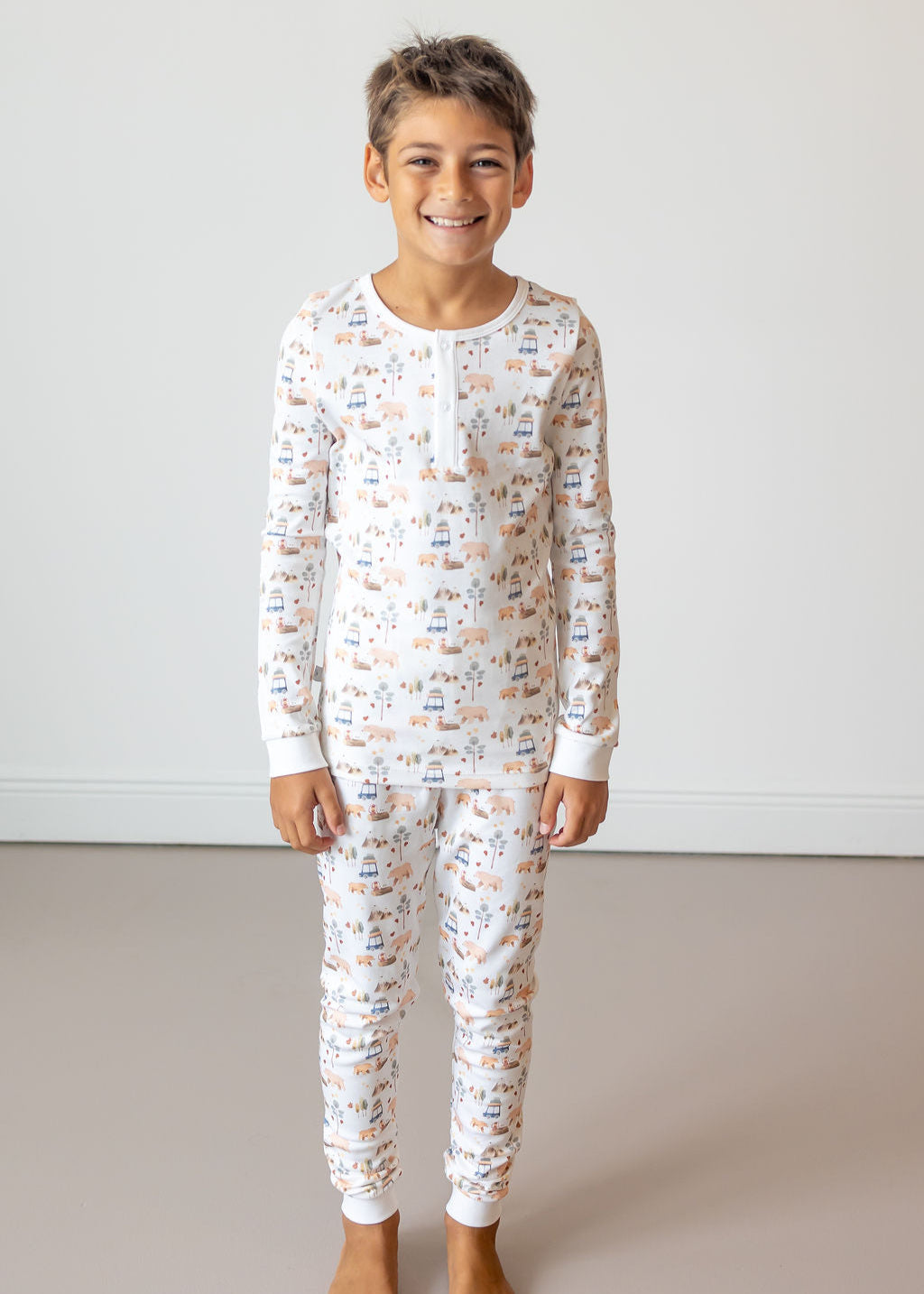 Child wearing a white pajama set with a pattern, standing against a plain background