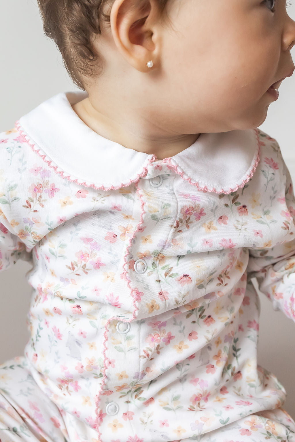 Close-up of a baby wearing a floral outfit with a white collar.