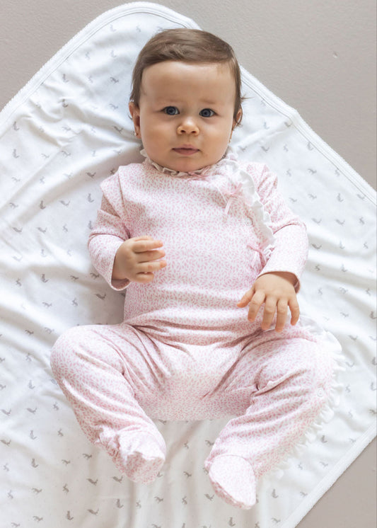 Baby in pink outfit lying on a white textured blanket
