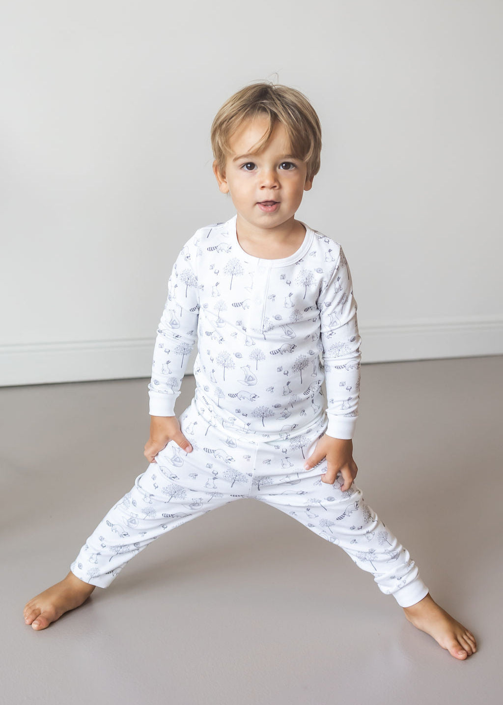 Child wearing a white long-sleeve shirt and pants with a pattern, standing on a neutral background.