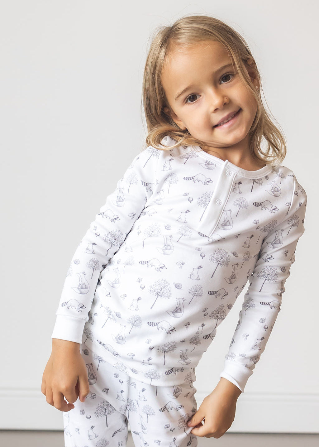 Child wearing a white long-sleeve shirt with small patterns on a plain background