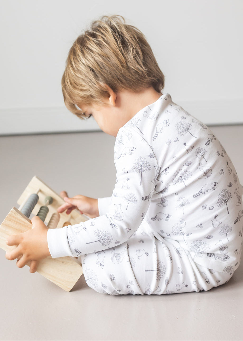Child playing with wooden toys on a light-colored floor.