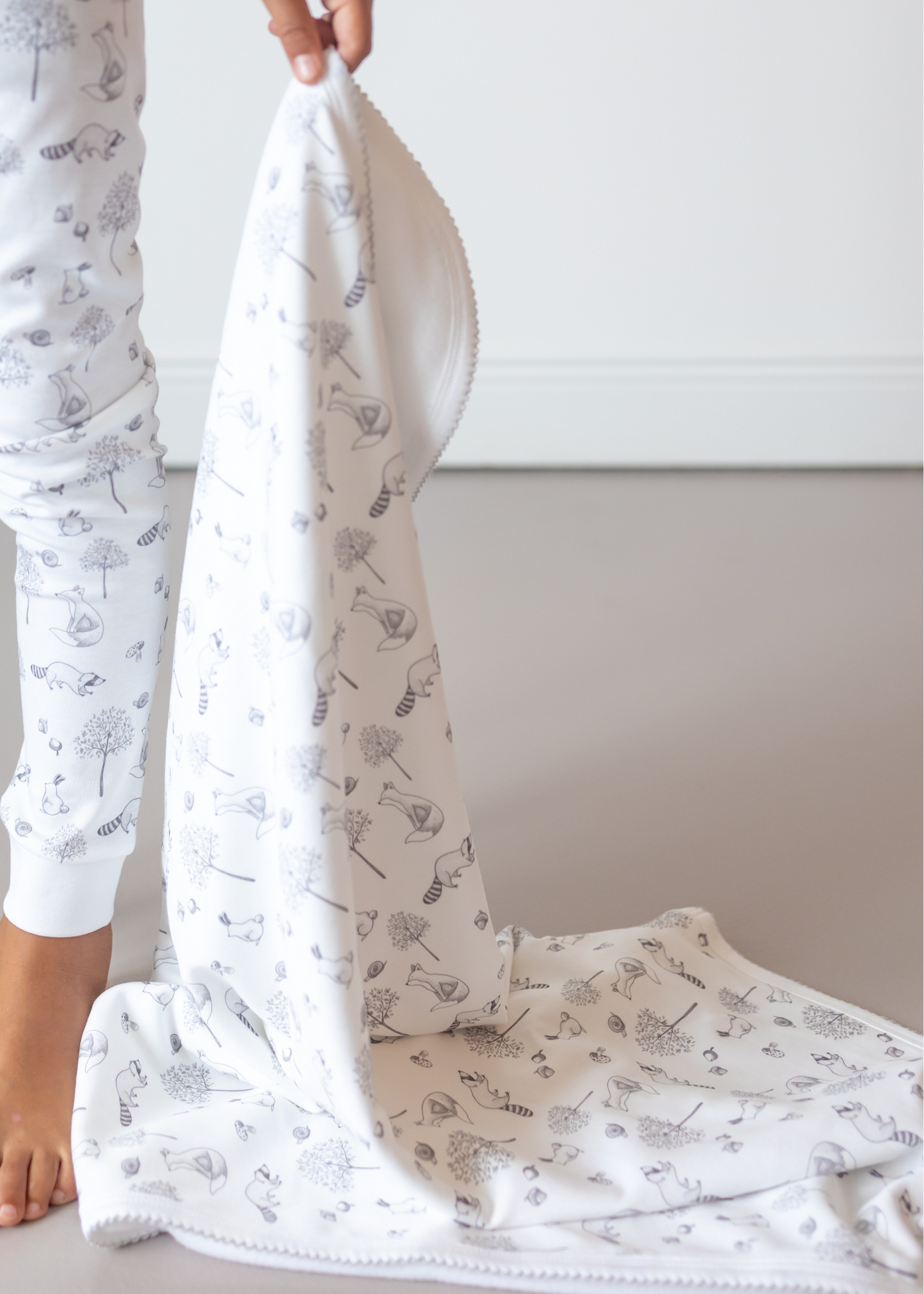 Person holding a white blanket with subtle patterns on a neutral background