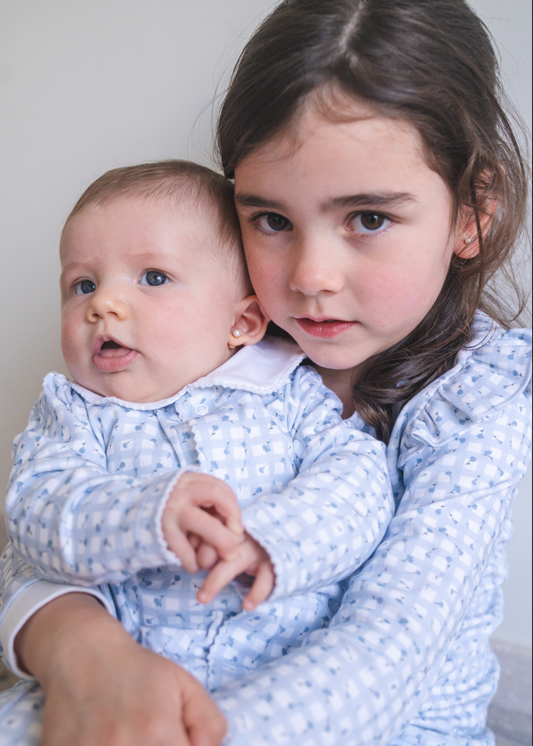 Two children in matching blue outfits sitting together.