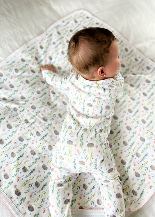 Baby in a patterned outfit on a crib with a white sheet