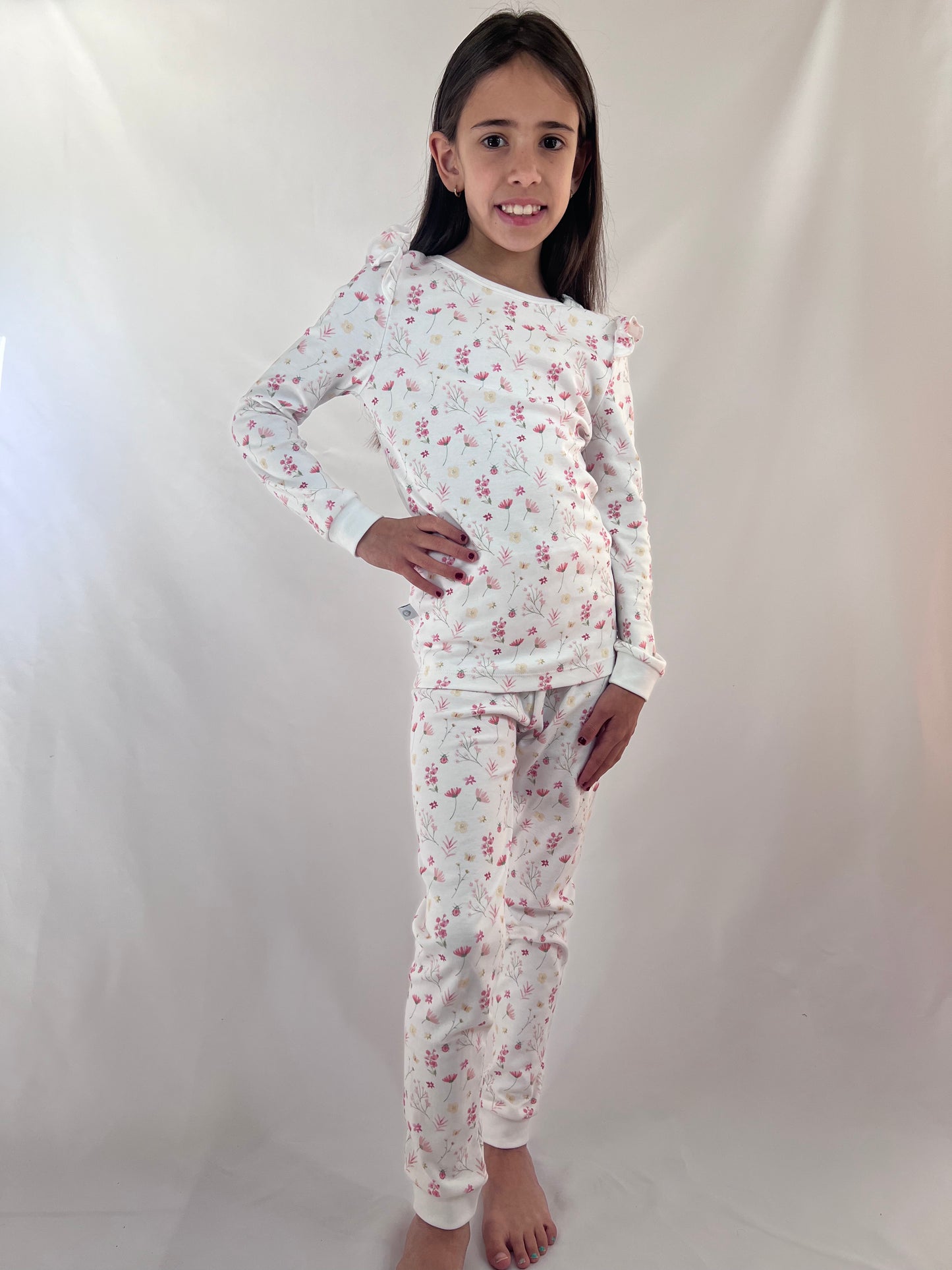 Young girl wearing a floral pajama set against a white background