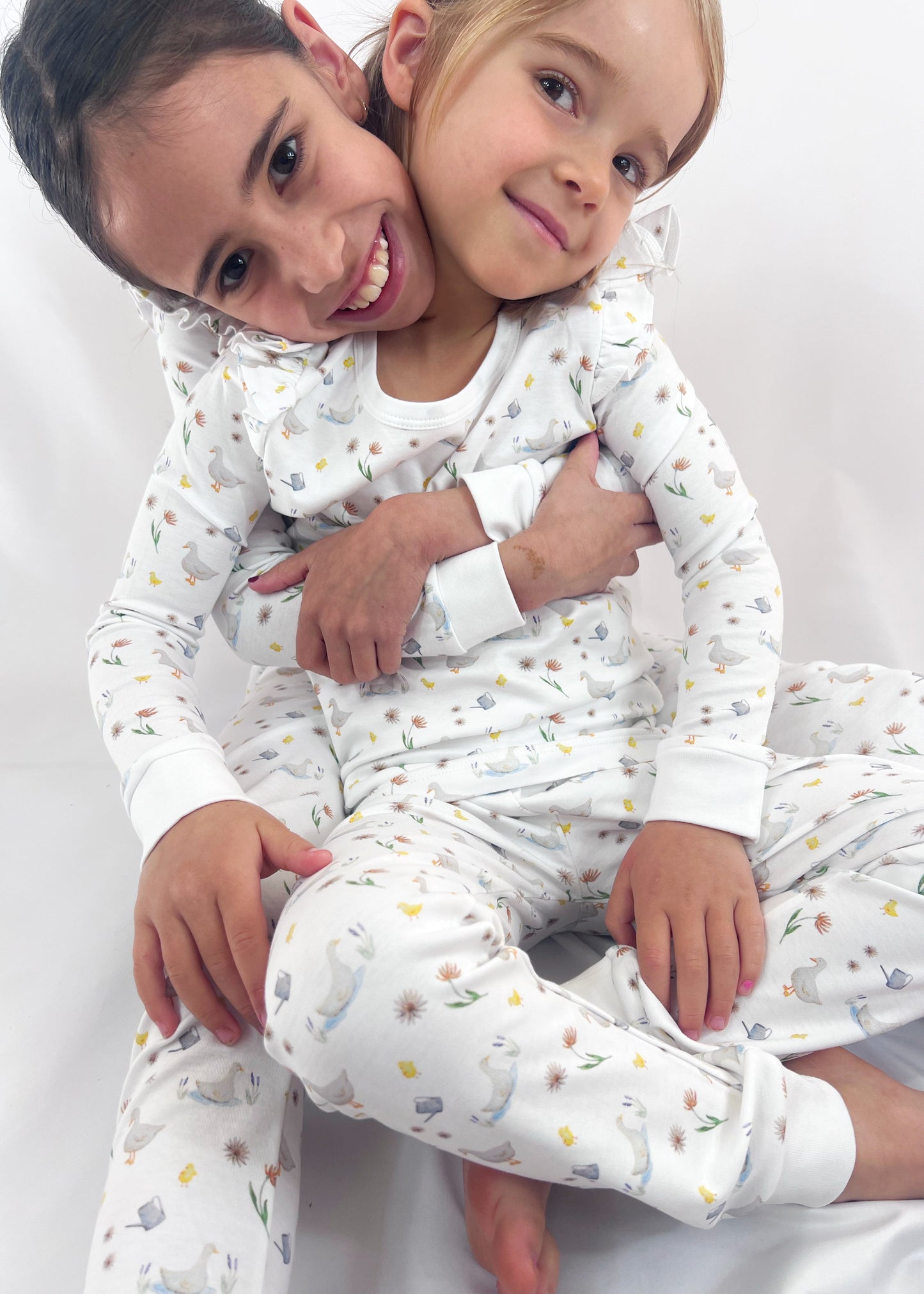 Two children in matching pajamas sitting on a white background