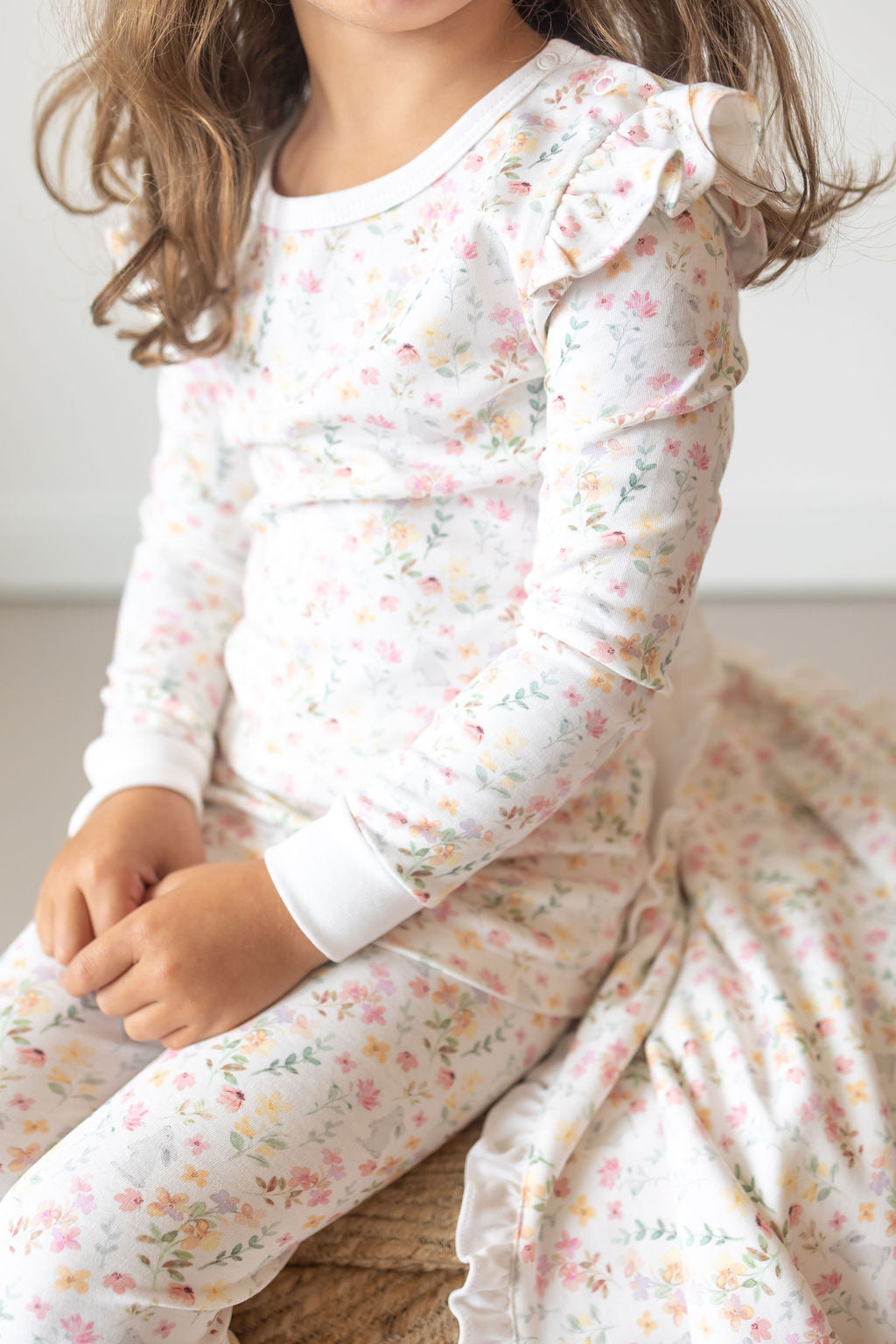 Child wearing a floral outfit with ruffled sleeves and bottom.