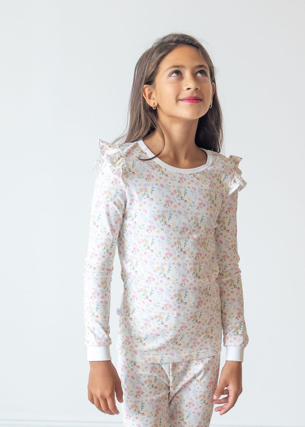 Young girl wearing a floral pajama set against a white background