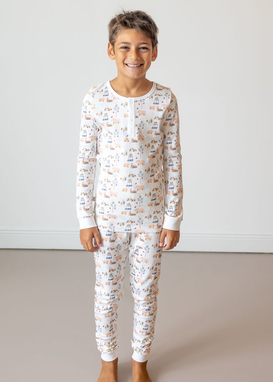 Child wearing a white pajama set with a pattern, standing against a plain background