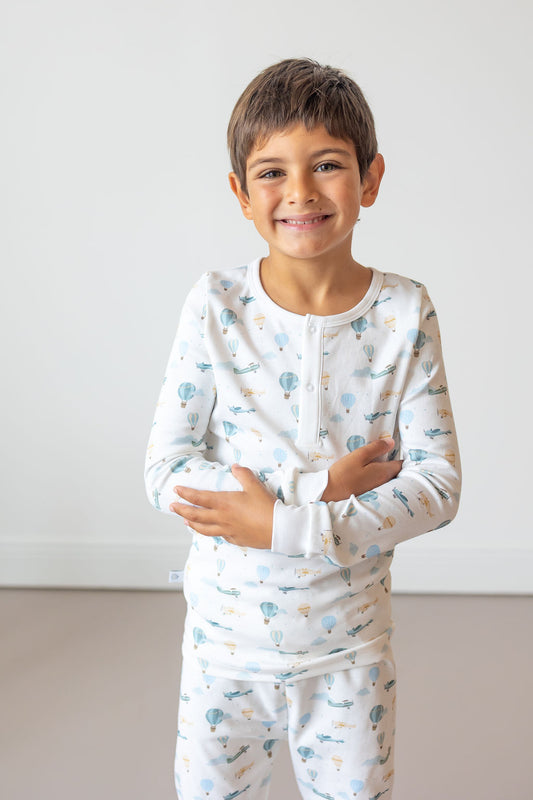 Child wearing a white long-sleeve shirt and pants with blue patterns on a plain background