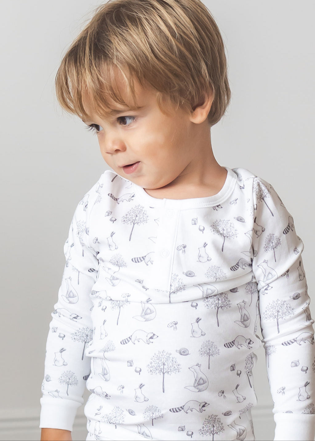Child wearing a white long-sleeve shirt with a dandelion pattern against a plain background