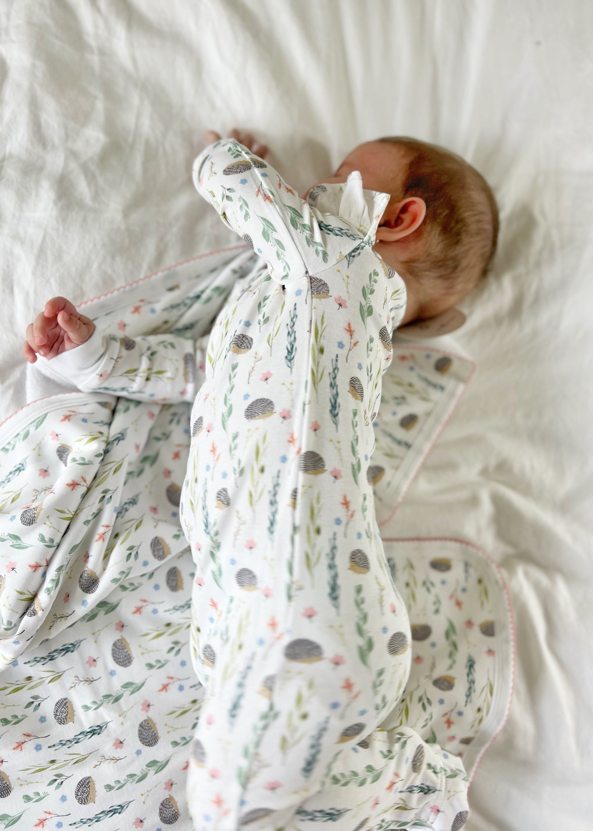 Baby wrapped in a floral-patterned swaddle on a white bed
