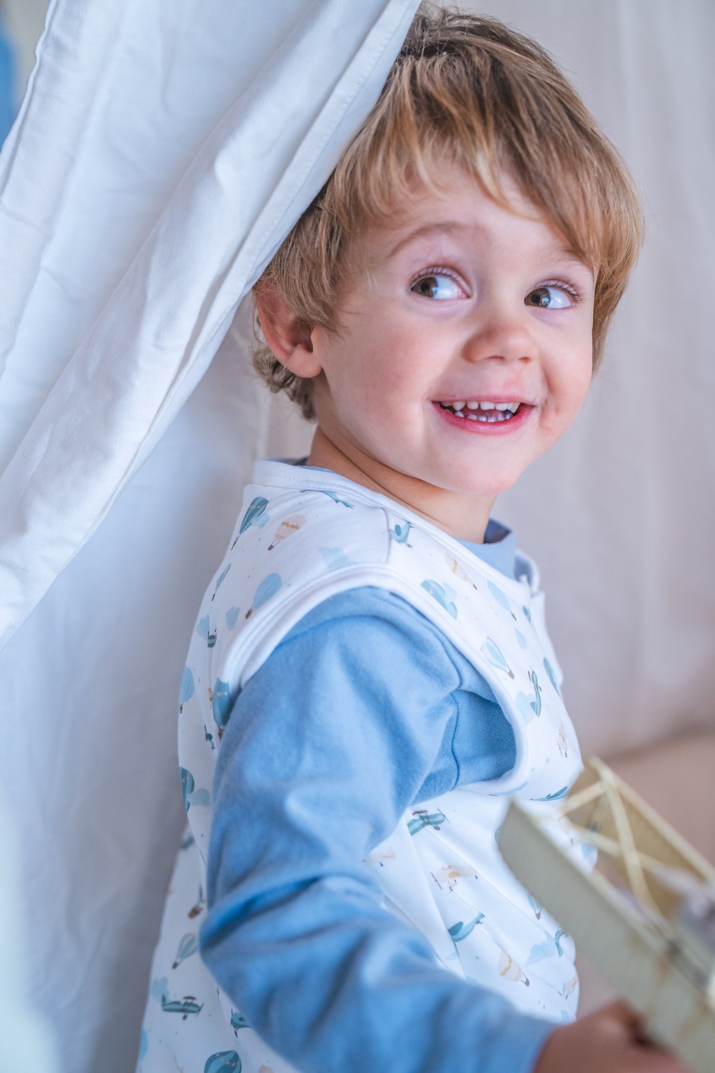 Child wearing a bib with a white curtain in the background
